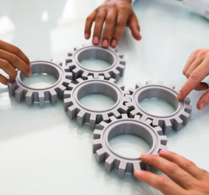Close-up Of Business People`s Hand Connecting Gears On Desk 